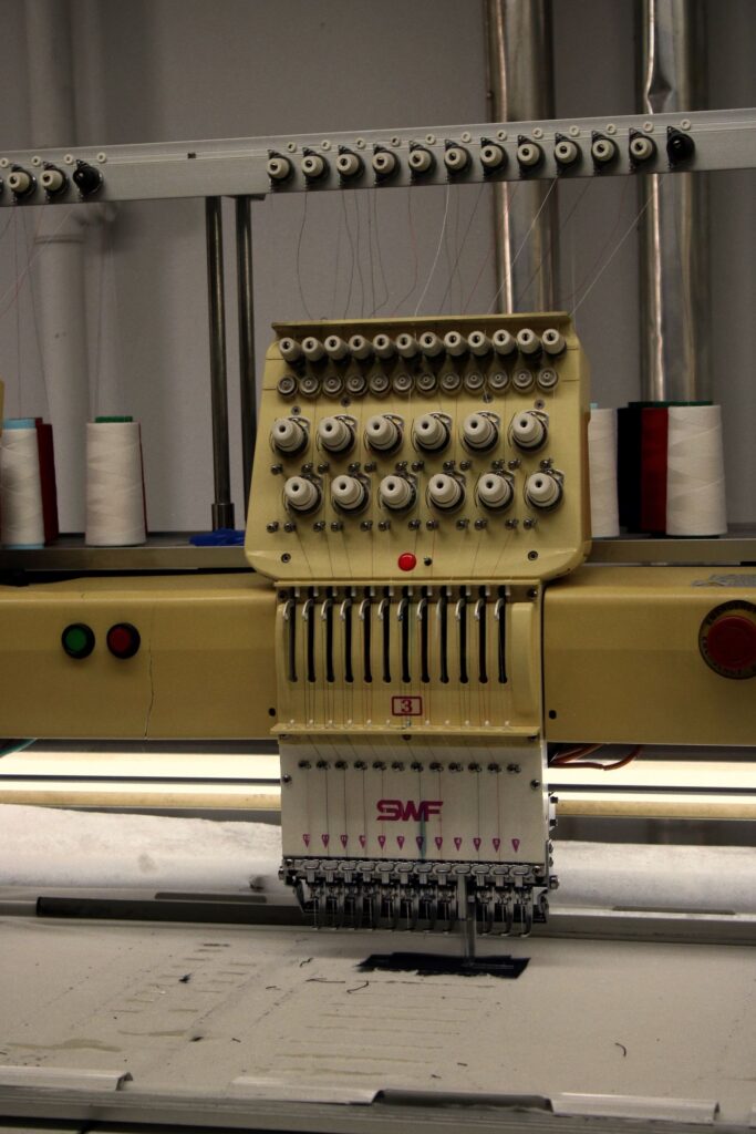 Máquina de bordado industrial con carretes de hilo — bordado de logos en XtremeSport